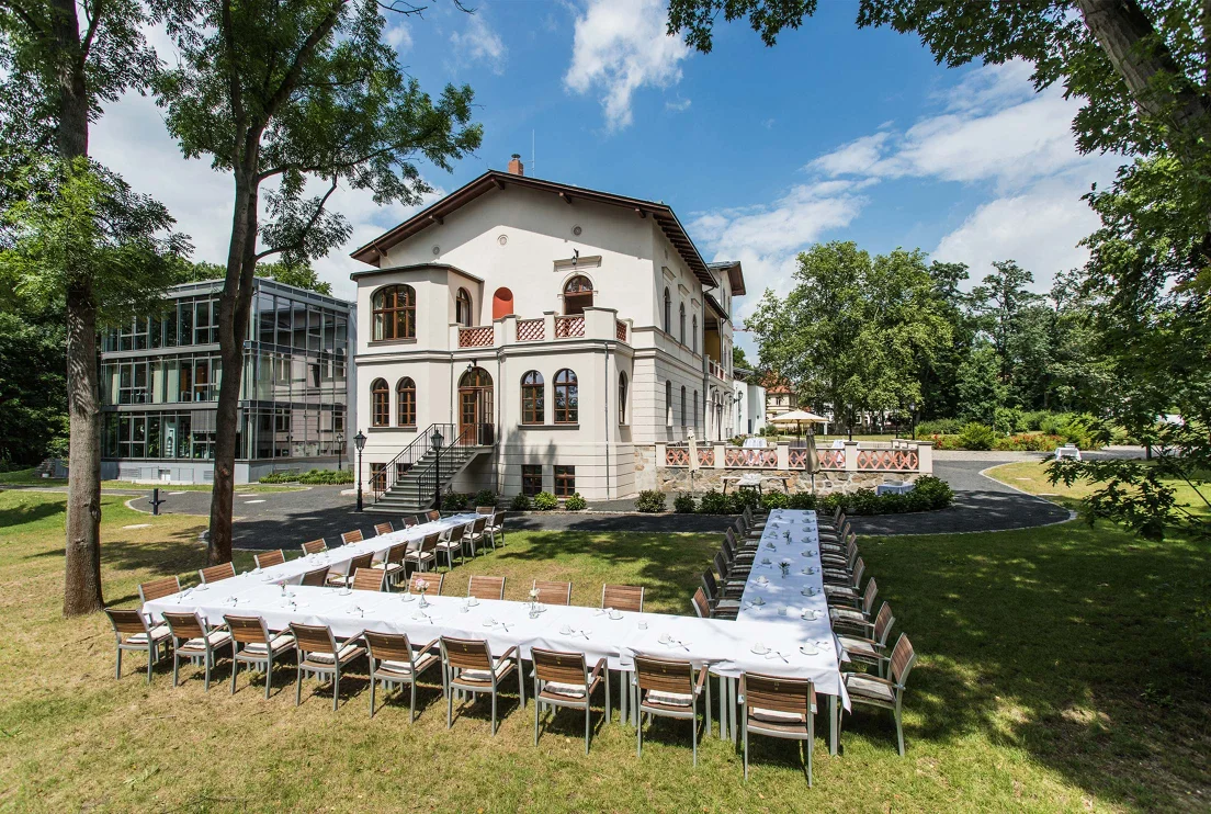 Außenansicht des Herrenhaus Möckern mit einer großen U-förmigen und festlich geschmückten Tafel im Garten 