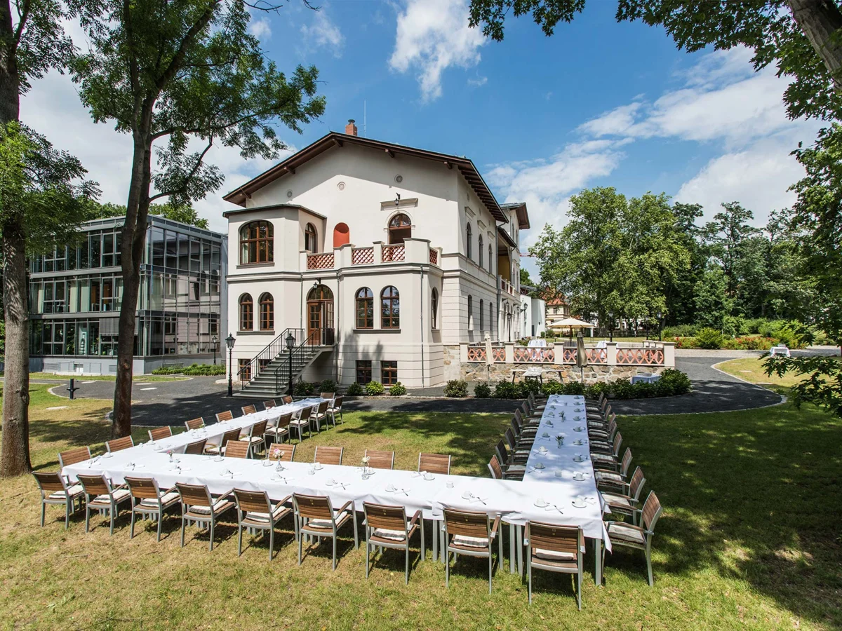 Außenansicht des Herrenhaus Möckern mit einer großen U-förmigen und festlich geschmückten Tafel im Garten 