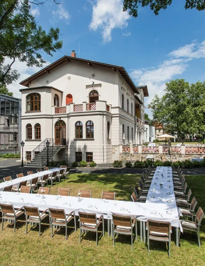 Außenansicht des Herrenhaus Möckern mit einer großen U-förmigen und festlich geschmückten Tafel im Garten