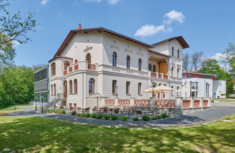 Außenansicht des Herrenhaus Möckern mit historischer Fassade, Terrasse mit Sitzgelegenheiten und umgebendem Garten